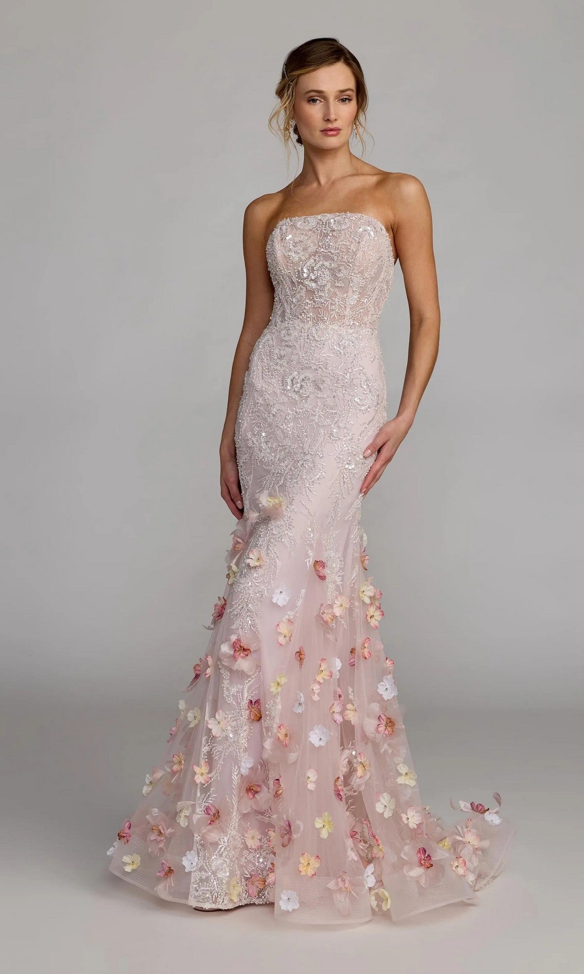 A woman poses against a plain gray background wearing the Mac Duggal 21147 long formal dress—a strapless mermaid gown with lace details and 3D floral appliques on a light pink tulle skirt.